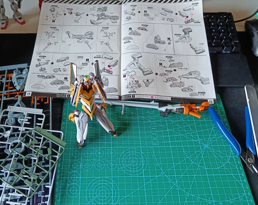 Half-built model kit on the workbench, instruction manual open, runners and nippers around it